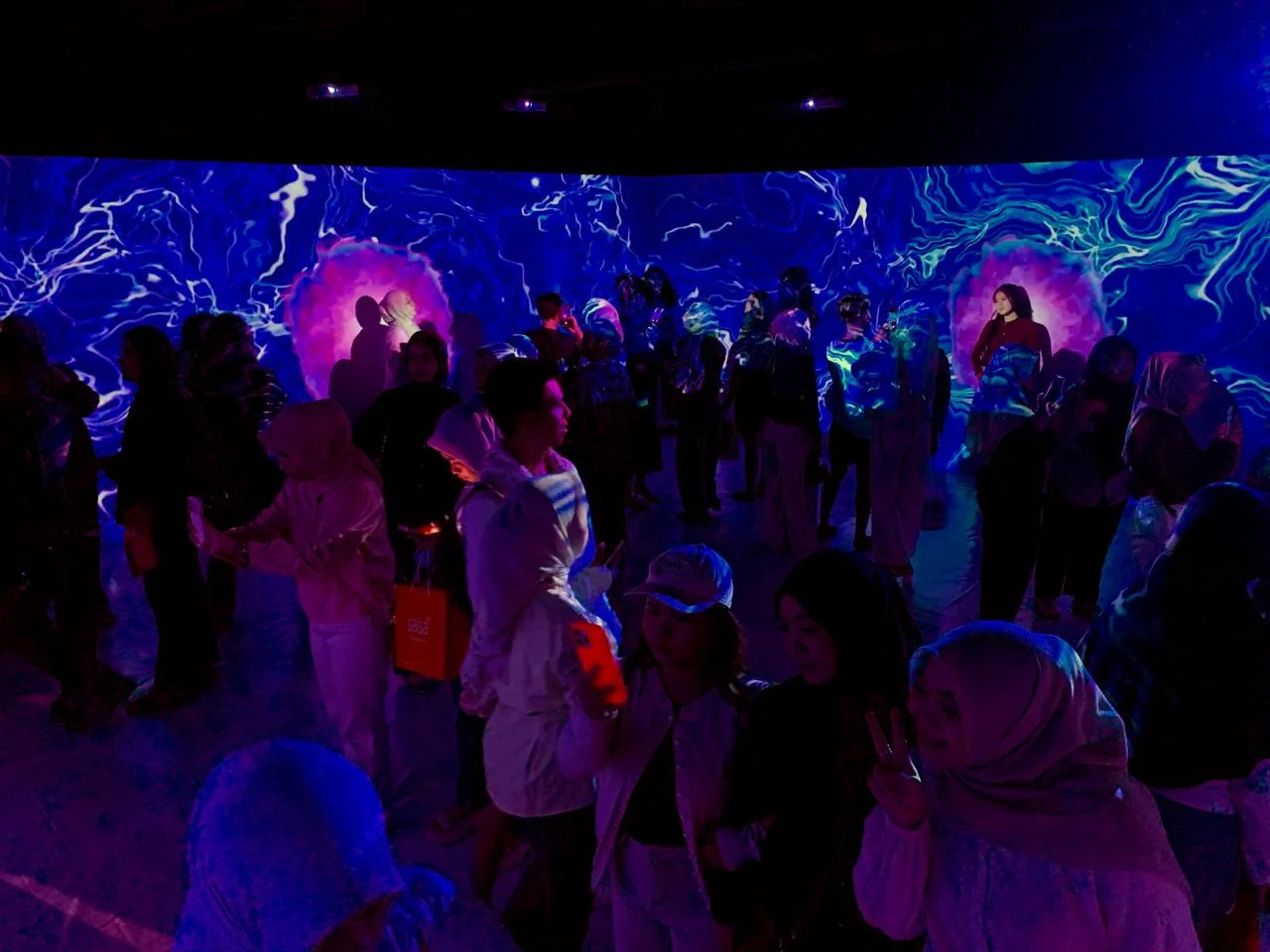 Pengunjung berada di antara proyeksi visual berskala ruang di Immersive Room.
