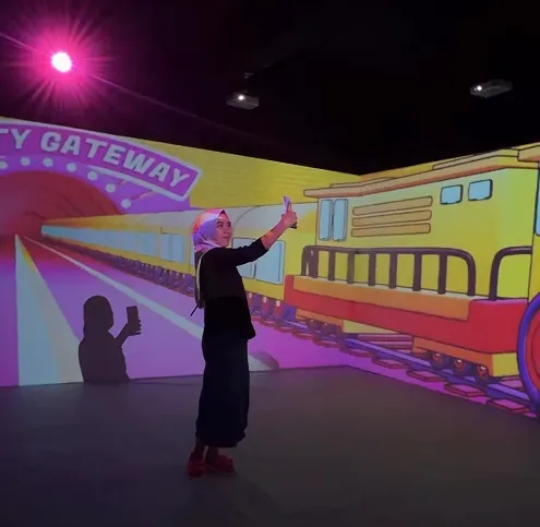 Pengunjung berekspresi di depan proyeksi visual berskala ruang.