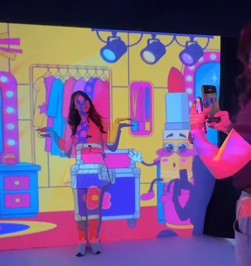 Interaksi pengunjung dengan latar proyeksi berwarna cerah di Immersive Room.